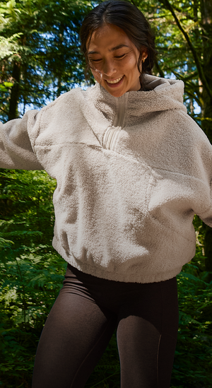 person wearing a beige fleece jacket in a forest setting. 