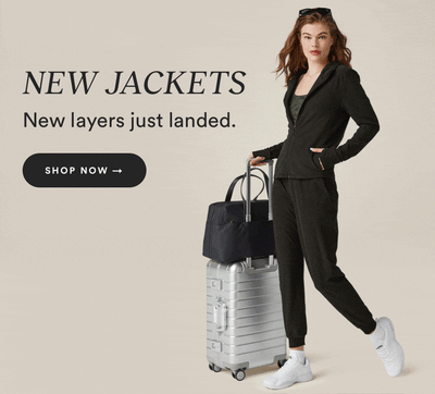 model is wearing a black zip-up hooded jacket and black high-waisted midi jogger pants. 