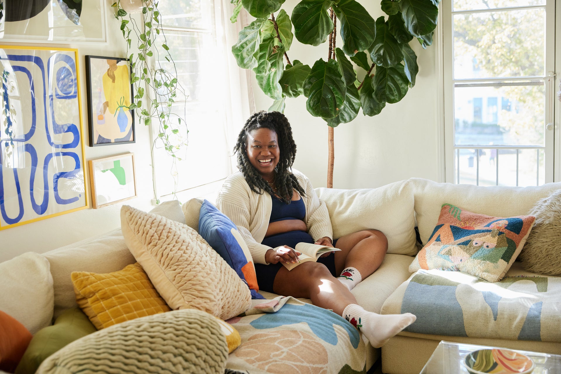 Photo of Kristina smiling on couch with a book