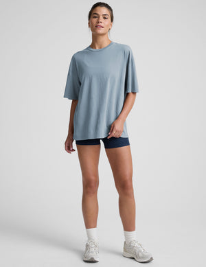 model wearing a light blue oversized cotton t-shirt and navy blue biker shorts against a plain background. 