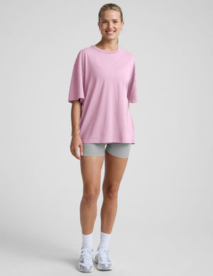 model wearing a pink oversized cotton t-shirt and grey biker shorts against a plain background. 