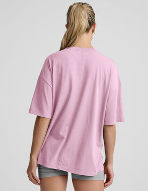 model wearing a pink oversized cotton t-shirt and grey biker shorts against a plain background. 
