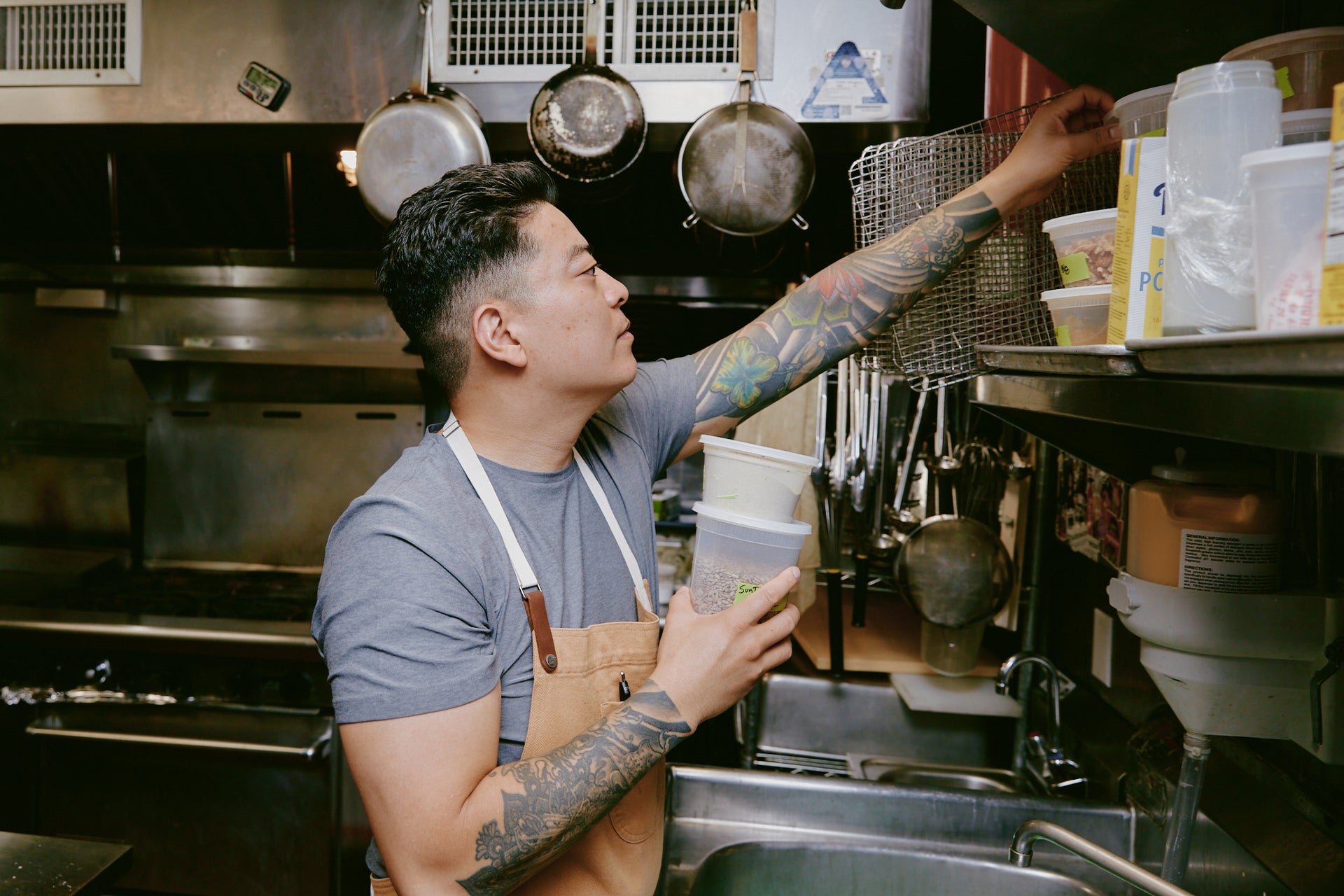 Jae reaching for container in kitchen