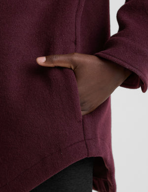 woman wearing a burgundy shirt jacket on a plain background. 