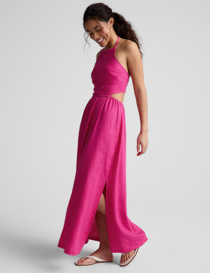 Woman wearing a pink halter neck midi dress on a plain background. 