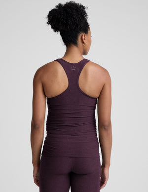 model wearing a purple maternity racerback tank top and leggings against a gray background. 
