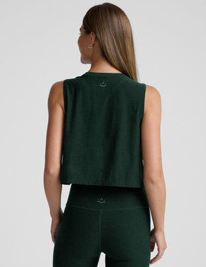 model wearing a green sleeveless cropped top and green leggings on a light gray background. 