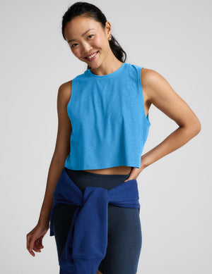 Woman wearing a light blue sleeveless top and biker shorts against a plain background. 