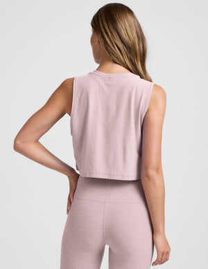 woman wearing a pink sleeveless cropped top and leggings against a plain background. 