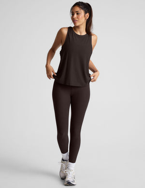 model wearing a brown sleeveless scoop neck top and leggings on a plain background. 