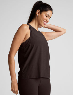 model wearing a brown sleeveless scoop neck top and leggings on a plain background. 