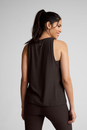 model wearing a brown sleeveless scoop neck top and leggings on a plain background. 