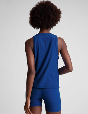 Woman wearing a blue relaxed fit sleeveless top and shorts on a plain background. 