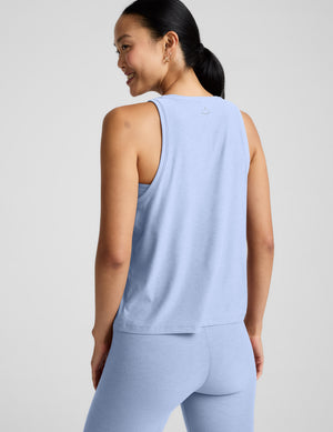 Woman wearing a light blue sleeveless top and leggings against a plain background. 