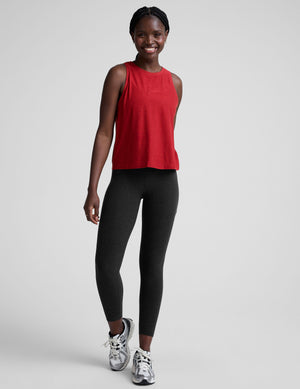 model wearing a red scoop neck sleeveless top and black leggings against a plain background. 