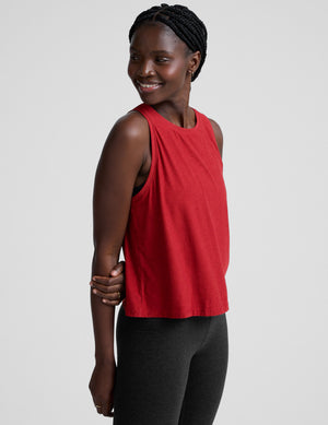 model wearing a red scoop neck sleeveless top and black leggings against a plain background. 