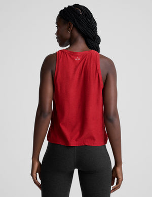 model wearing a red scoop neck sleeveless top and black leggings against a plain background. 