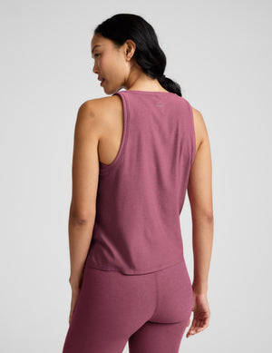 Person wearing a mauve tank top and leggings on a light gray background. 