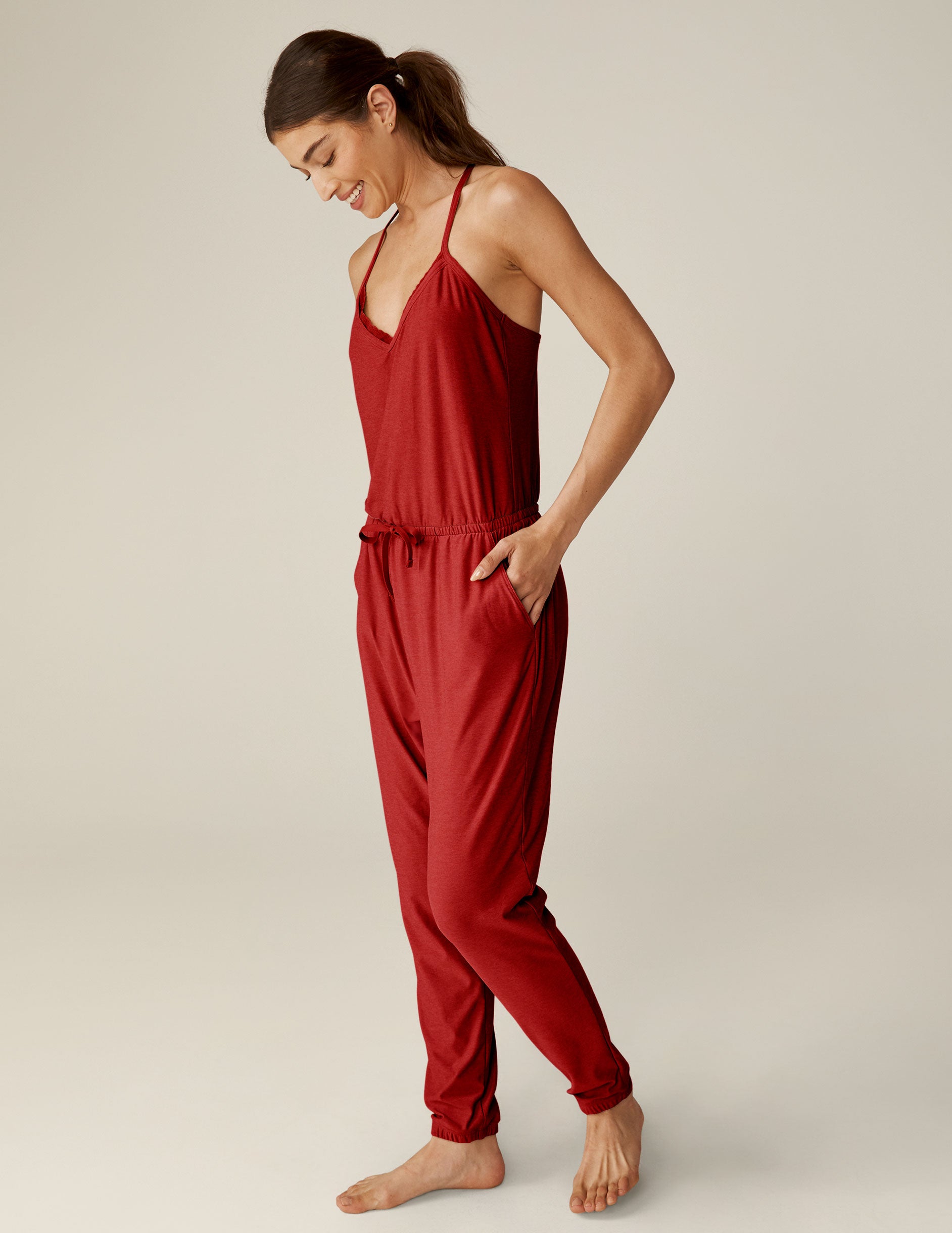 red racerback jogger jumpsuit with scalloped lace detailing on the neckline and a drawstring at waist. 