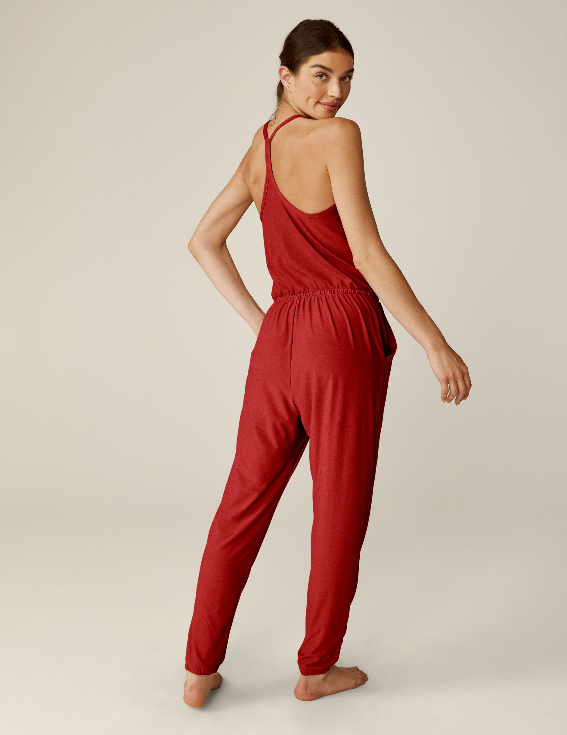 red racerback jogger jumpsuit with scalloped lace detailing on the neckline and a drawstring at waist. 