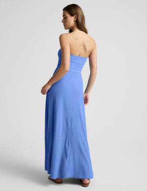 Woman wearing a blue strapless maxi dress against a light gray background. 