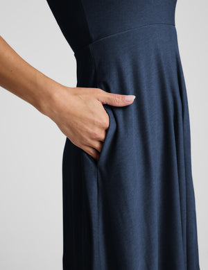 Woman wearing a blue sleeveless dress on a white background. 