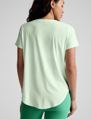 Woman wearing a light green t-shirt and green leggings on a white background. 