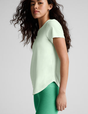 Woman wearing a light green t-shirt and green leggings on a white background. 