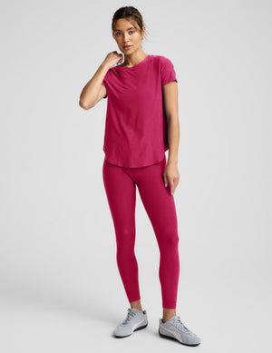 Woman wearing a red t-shirt and red leggings against a plain background. 