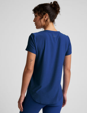 Woman wearing a blue crew neck t-shirt and leggings on a light gray background. 