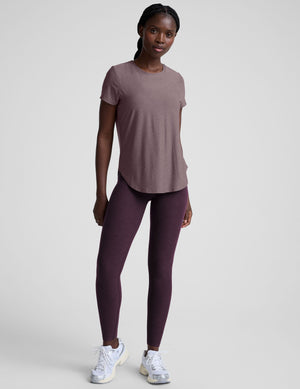 model wearing a mauve t-shirt and leggings on a plain background. 