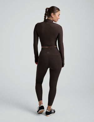 model wearing a brown mock neck cropped long sleeve against a plain background. 