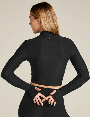 Woman wearing a black long-sleeve top and leggings on a beige background