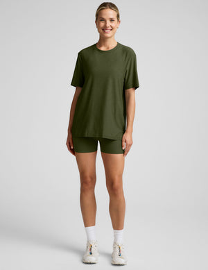 model wearing a green oversized men's t-shirt and biker shorts against a plain background. 