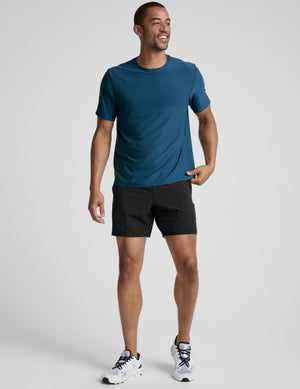 man wearing a blue t-shirt and black shorts against a plain background. 