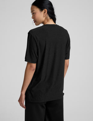 Person wearing a black t-shirt and black pants on a gray background. 