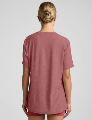 model wearing an oversized men's red t-shirt and shorts on a plain background. 