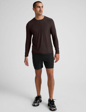 model wearing a brown men's long-sleeve shirt against a gray background.
