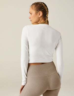 white scoop neck featherweight long sleeve cropped top with a front crossover detail. 