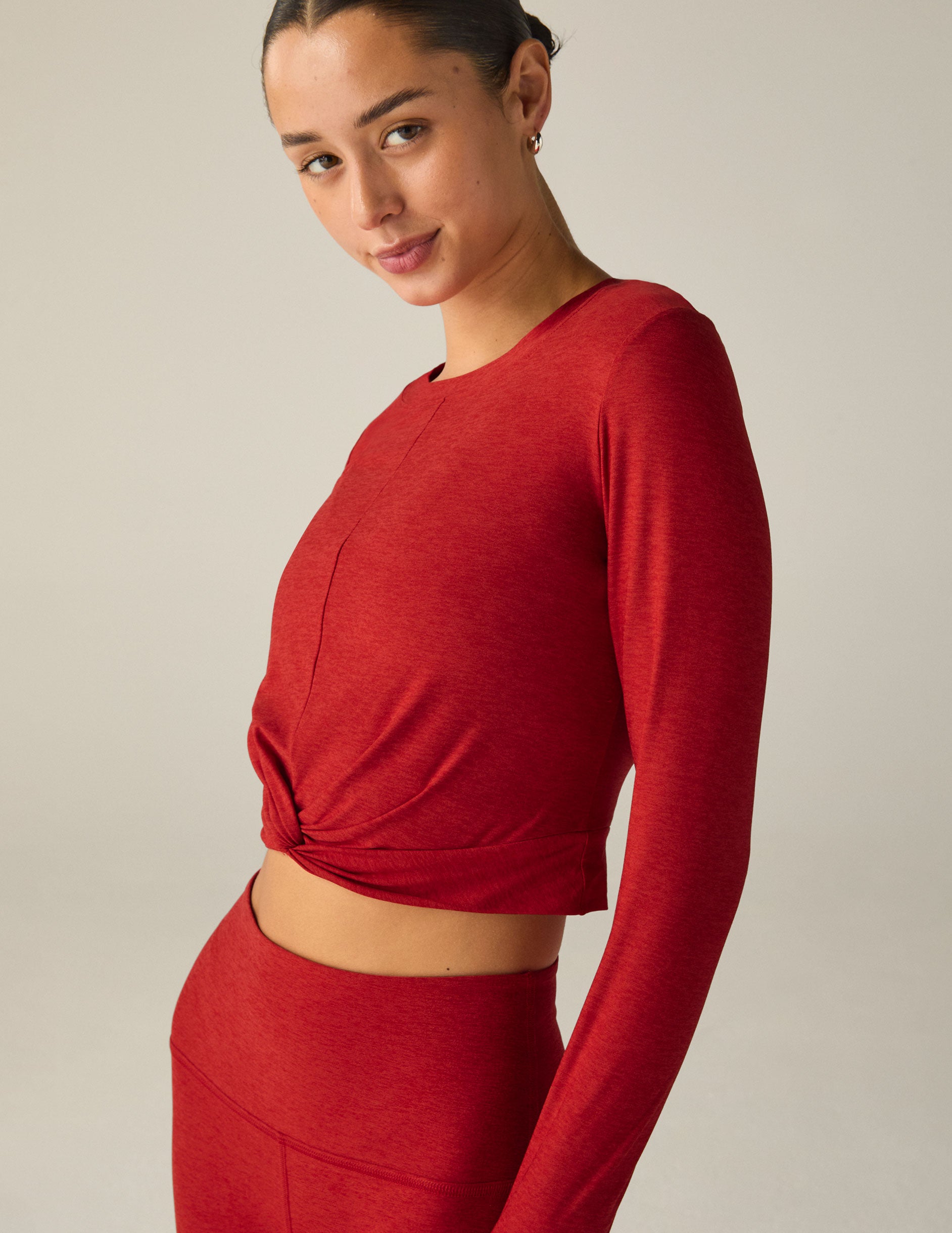 red long sleeve top with a twist detail in front. 