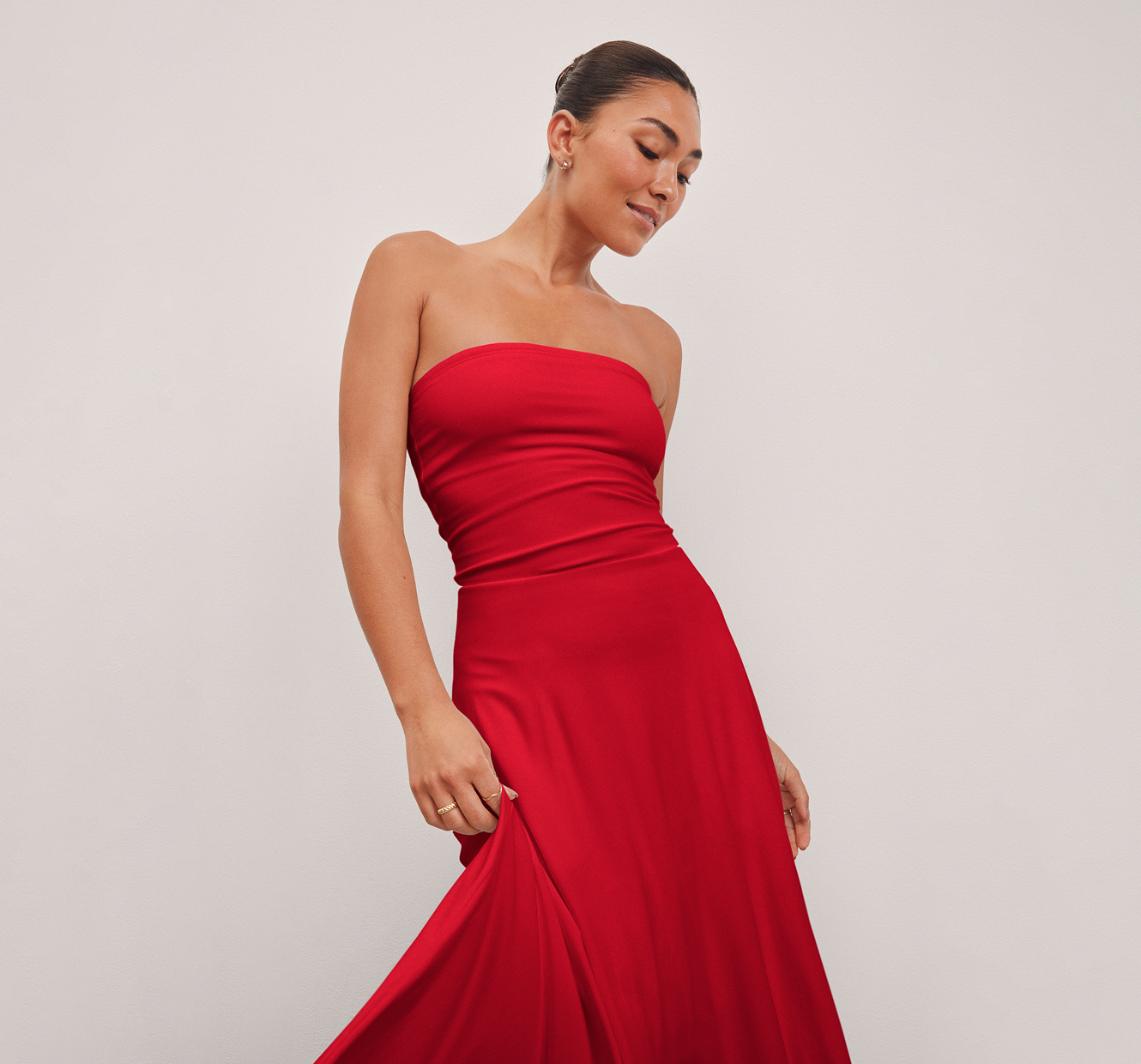 model is wearing a red strapless midi length dress. 