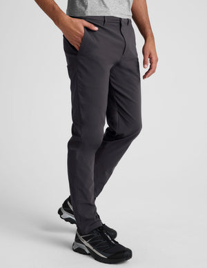 male model wearing a grey t-shirt and chino pants on a light background. 