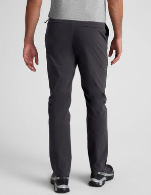 male model wearing a grey t-shirt and chino pants on a light background. 