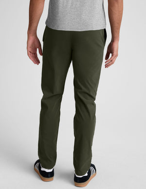 model wearing green men's chino pants on a plain background. 