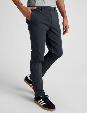man wearing a gray t-shirt and navy chino pants with pockets against a plain background. 