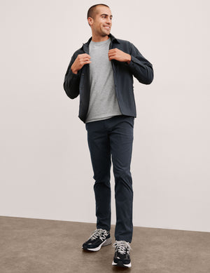 man wearing a gray t-shirt and navy chino pants with pockets against a plain background. 