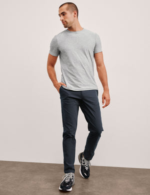 man wearing a gray t-shirt and navy chino pants with pockets against a plain background. 