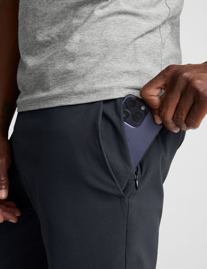 man wearing a gray t-shirt and navy chino pants with pockets against a plain background. 