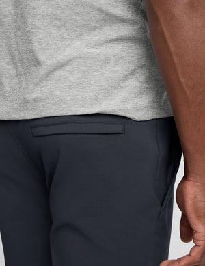 man wearing a gray t-shirt and navy chino pants with pockets against a plain background. 