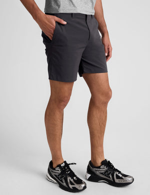 man wearing a grey crew neck t-shirt and black chino shorts with pockets on a plain background. 